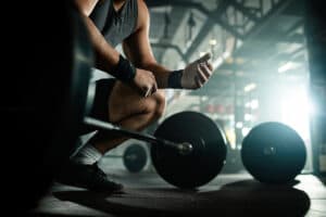 vista-de-angulo-baixo-homem-de-construcao-muscular-irreconhecivel-se-preparando-para-levantar-uma-barra-em-um-clube-de-saude-560367