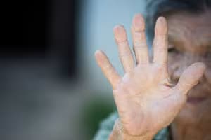 close up picture of old woman’s hand showing anti symbol