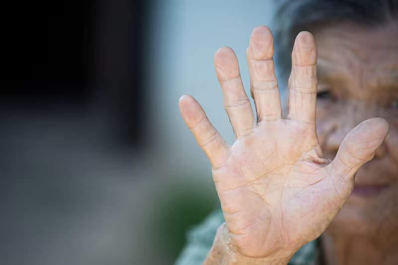 close up picture of old woman’s hand showing anti symbol