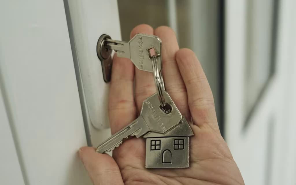 Mão segurando chaves de casa perto da fechadura