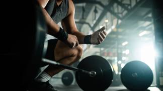 vista-de-angulo-baixo-homem-de-construcao-muscular-irreconhecivel-se-preparando-para-levantar-uma-barra-em-um-clube-de-saude